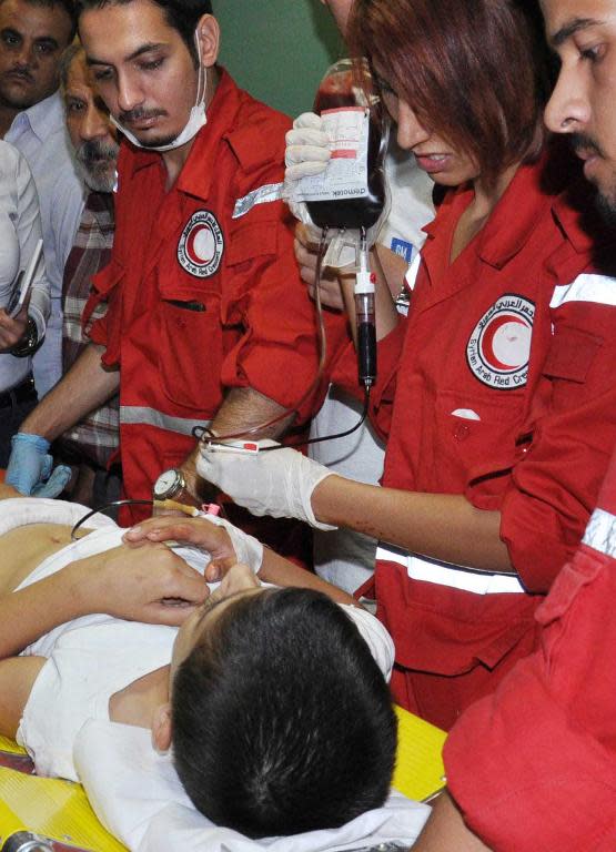 A picture released by the official Syrian Arab News Agency reportedly shows Syrian Red Crescent members providing medical assistance to a victim a car bomb explosion outside the Akrameh al-Makhzumi school in Homs on October 1, 2014