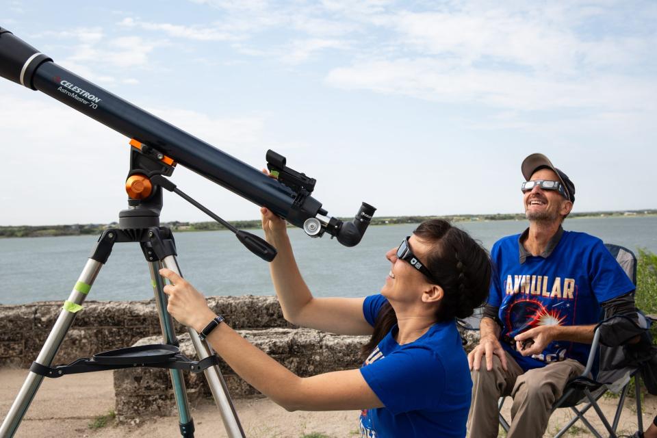 A couple in Katy, Texas watch an annular solar eclipse Oct. 14 through viewing glasses and a telescope at Lake Corpus Christi State Park in Mathis, Texas.