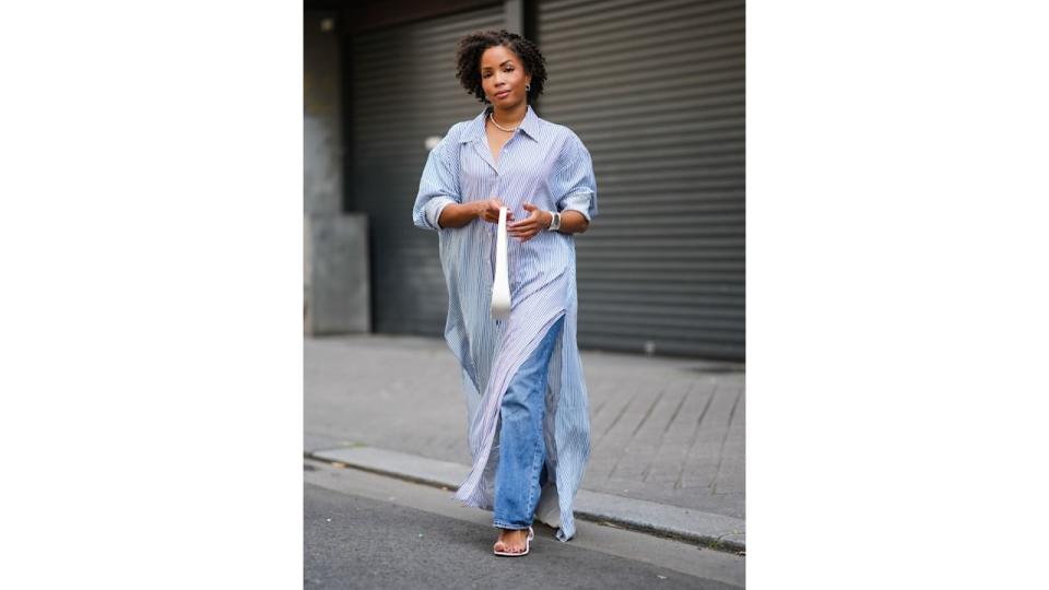 Ellie Delphine wears a white long maxi shirt dress with stripes from The Frankie Shop teamed with a white bag from The Row.