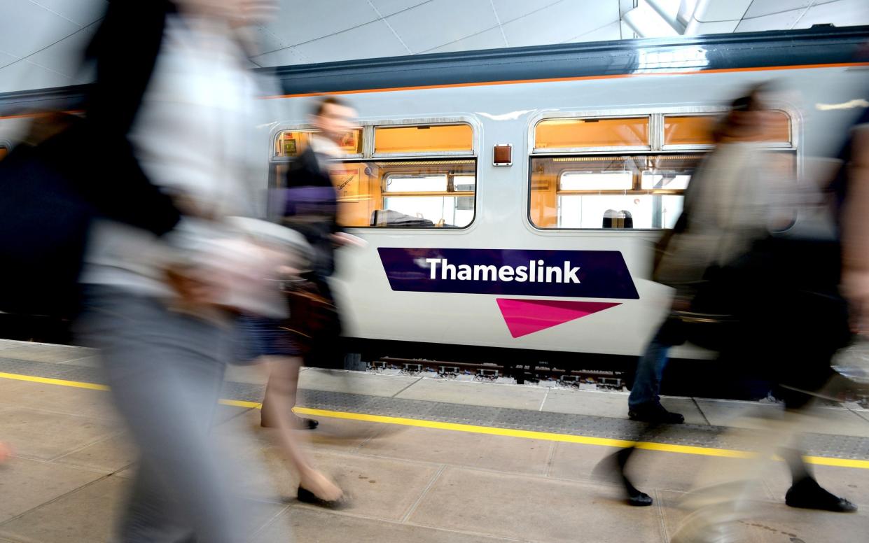 Passengers walk past a Thameslink train