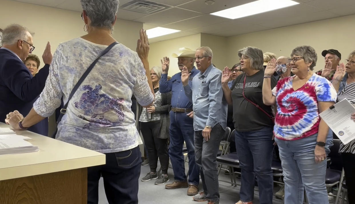 In this image from video, Nye County Clerk Mark Kampf, far left, in suit, swears in a group of residents who will hand count early ballots cast in the rural county about halfway between Las Vegas and Reno, on Wednesday, Oct. 26, 2022, in Pahrump, Nev. Nye is the largest county in the U.S. to attempt a hand count of all its ballots in the midterm elections, a change fueled by conspiracy theories about voting machines. (AP Photo/Gabe Stern