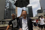 Occupy Central leader Benny Tai, center, is accompanied by a supporter who raises an umbrella as he leaves High court in Hong Kong Thursday, Aug. 15, 2019. Tai, a top opposition leader imprisoned on public disorder charges was released on bail Thursday as Hong Kong's government attempts to quell a protest movement that has paralyzed parts of the territory, including its international airport, and led to hundreds of arrests. (AP Photo/Vincent Yu)
