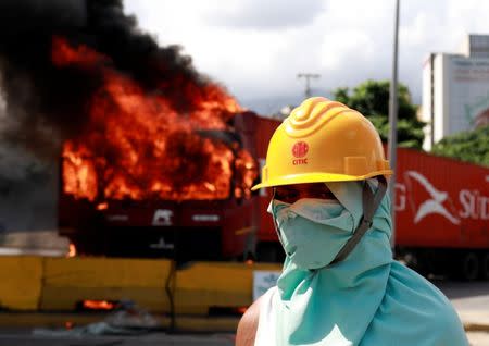 A demonstrator looks on as trucks set on fire burn on a highway during a rally against Venezuela's President Nicolas Maduro's Government in Caracas, Venezuela, June 23, 2017. REUTERS/Marco Bello