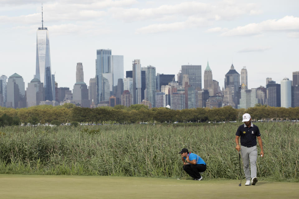 With the New York skyline in the distance, Patrick Reed, left, and Abraham Ancer look at their prospective putts on the 14th green at the Northern Trust golf tournament at Liberty National Golf Course, Sunday, Aug. 11, 2019, in Jersey City, N.J. (AP Photo/Mark Lennihan)