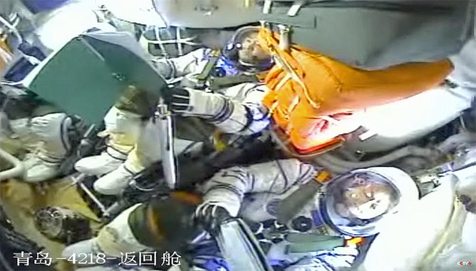 An ink pen drifts in the Shenzhou 14 crew cabin moments after the spacecraft reached orbit. Mission commander Chen Dong is visible at center with Cai Xuzhe strapped in at right. Crewmate Liu Yang is out of view to left. / Credit: CCTV