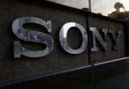 Pedestrians are reflected in a logo of Sony Corp outside its showroom in Tokyo July 16, 2014. REUTERS/Yuya Shino