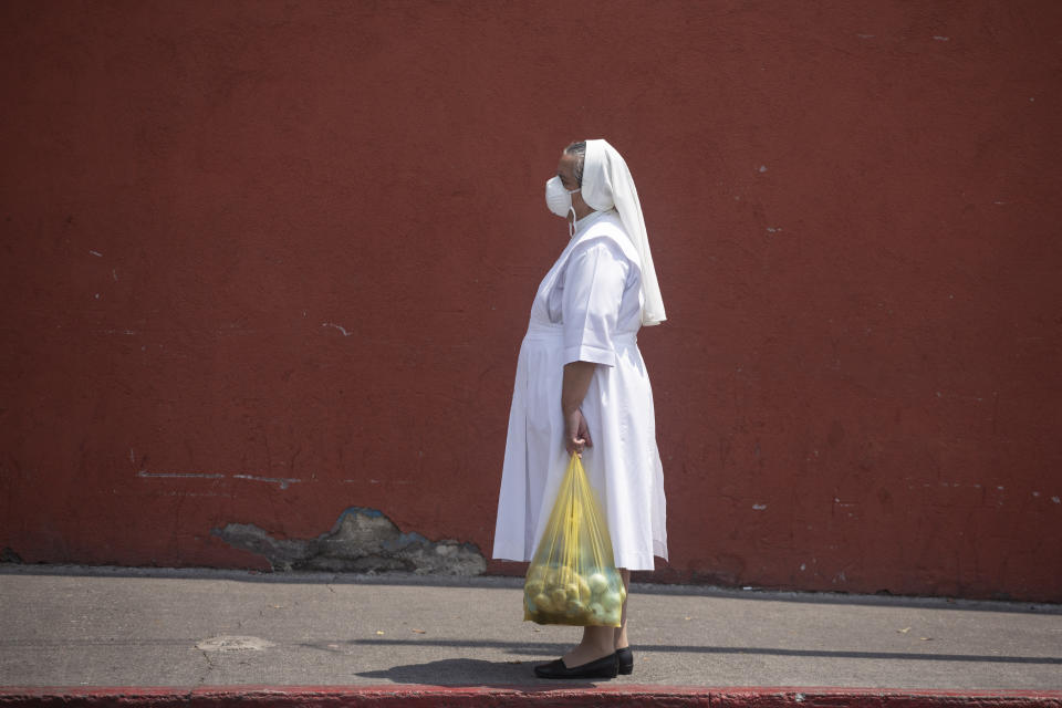 A nun, waring a mask to protect herself from the spread of the new coronavirus, stands near the closed Candelaria church in Guatemala City, Wednesday, April 8, 2020. Catholics prepare to celebrate Holy Week amid measures to prevent the spread of the coronavirus, including stopping all religious activities across the country. (AP Photo/Moises Castillo)