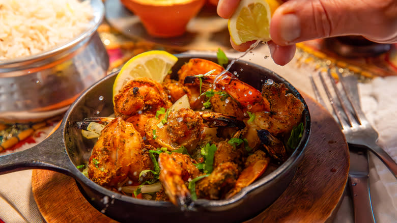 Squeezing lemon onto tandoori prawns