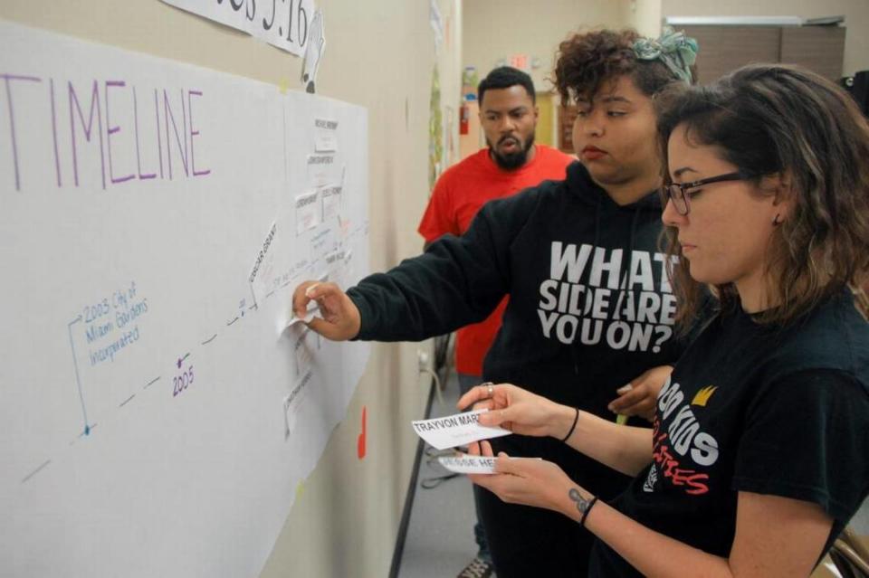 
Dream Defenders then-executive director, Phillip Agnew, and Dream Defenders members Shamile Louis, center, and Arely Lozano-Baugh, post notes written by members of the Miami Gardens community onto a poster on Feb. 21, 2015.