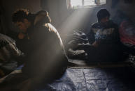 Bracing against harsh winter weather inside an abandoned house migrants are gathered near the Hungarian border, outside of the village of Martonosh, Serbia, Thursday, Jan. 13, 2022. Hungary's nationalist prime minister, Viktor Orban, is keen to use the threat of migrants at his country's southern border to give him an advantage in upcoming elections. But the scale of migration pressure claimed by Orban is drawn into question by statistics from neighboring Serbia and the European Union's border agency. (AP Photo/Bela Szandelszky)