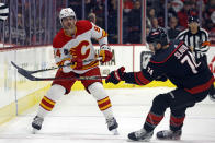 Calgary Flames' Brayden Pachal (94) dumps the puck past Carolina Hurricanes' Jaccob Slavin (74) during the first period of an NHL hockey game in Raleigh, N.C., Sunday, March 10, 2024. (AP Photo/Karl B DeBlaker)