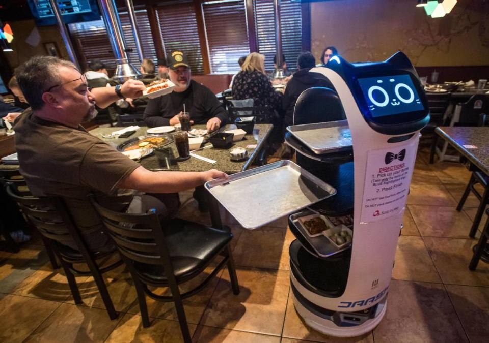 Dan Delcollo, of Granite Bay, takes his food from a tray delivered by one of two BellaBots at Oz Korean BBQ on Thursday.