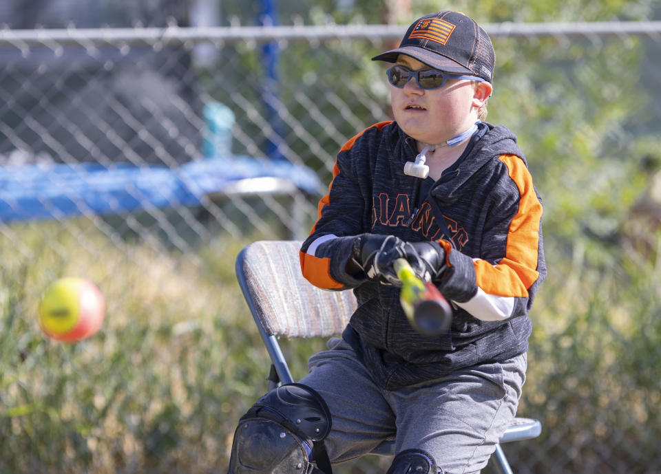 Brady Hill gets a hit during a baseball game with family at their home in Meridian, Idaho, June 19, 2023. Brady survived a rare brain cancer as a baby, but requires round the clock care. Families of severely disabled children across the country are worried about the future of crucial Medicaid payments they started receiving to provide care during the COVID-19 pandemic. (AP Photo/Kyle Green)