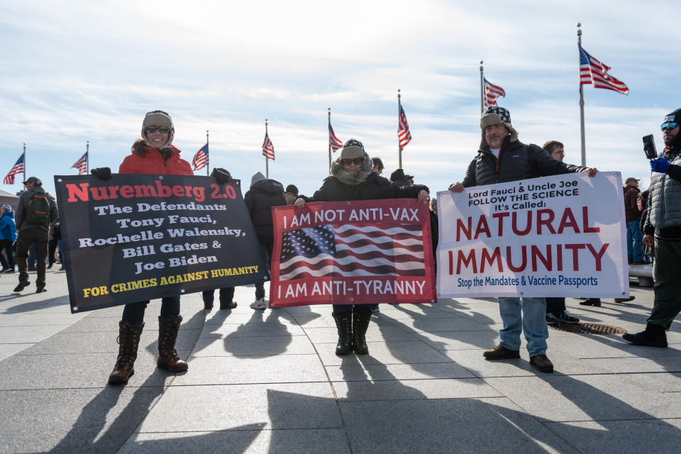 Demonstrators hold signs during an anti-vaccine mandate rally 