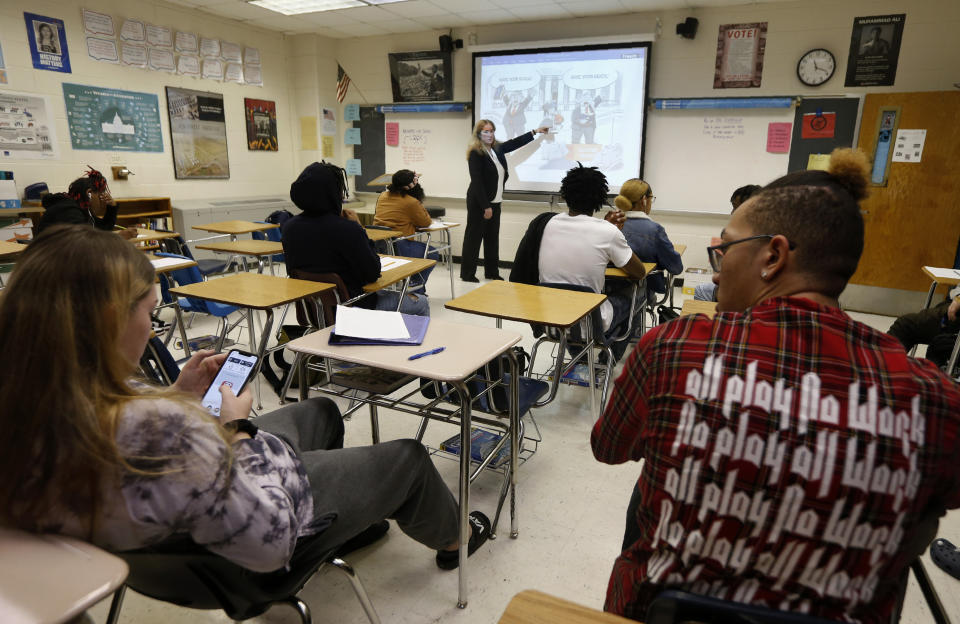 In this Wednesday, Feb. 5, 2020 photo, India Meissel, a history teacher and past president of the National Council on Social Studies, points out the bias in a political cartoon as she lectures her students at Lakewood High School in Suffolk, Va. Fairfax County Public Schools in Virginia is defending a recent partnership with the nonprofit educational group Izzit.org, in producing a video presentation from a conservative federal judge on the Constitution. Izzit.org is facing criticism that its materials are ideologically skewed. Meissel said some teachers might use Izzit material and see a need to balance it out with a different perspective. “A good teacher presents both sides,” she said. (AP Photo/Steve Helber)