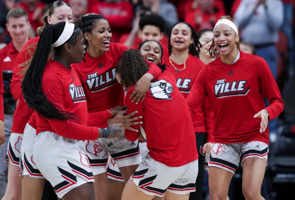 U of L's women's basketball team embraced teammate Mykasa Robinson (5) as she set a new program record for most career games played at 145 ahead of their game against NC State at the Yum Center in Louisville, Ky. on Jan. 22, 2023.