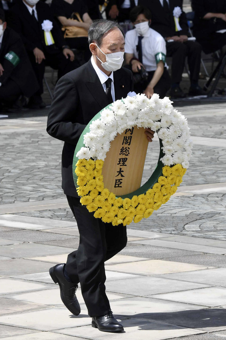 Japan's Prime Minister Yoshihide Suga offers a wreath during a ceremony at Nagasaki Peace Park in Nagasaki, southern Japan Monday, Aug. 9, 2021. The Japanese city of Nagasaki on Monday marked its 76th anniversary of the U.S. atomic bombing. (Kyodo News via AP)