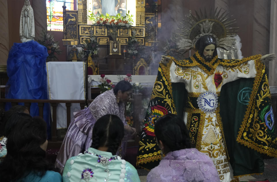 A devotee releases incense after dressing the statue of "Jesus del Gran Poder" or Lord of Great Power, at the "Jesus del Gran Poder" church in La Paz, Bolivia, Thursday, June 1, 2023. Thousands of dancers and musicians will parade on Saturday to show their devotion and thank God and for the year's blessings. (AP Photo/Juan Karita)