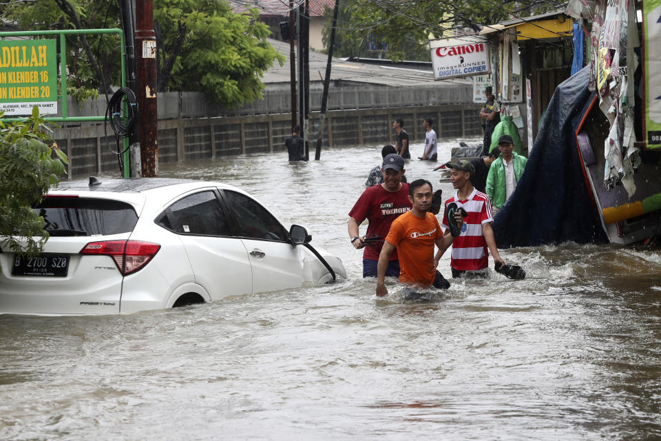 Indonesian people wade through floodwaters in Jakarta, Indonesia, Wednesday, Jan. 1, 2020. Severe flooding hit Indonesia's capital just after residents celebrating New Year's Eve, forcing a closure of an airport and thousands of inhabitants to flee their flooded homes.(AP Photo/Achmad Ibrahim)