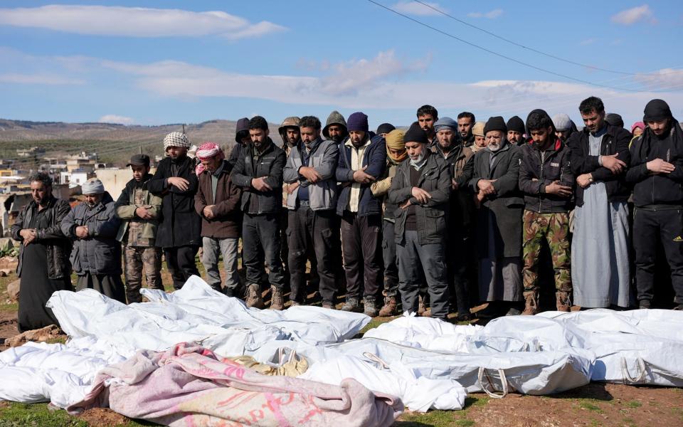 Syrians mourn over the bodies of a family and close neighbours in the village of Hajji Iskandar who were killed as their family home collapsed during the deadly earthquake. - Rami al SAYED / AFP