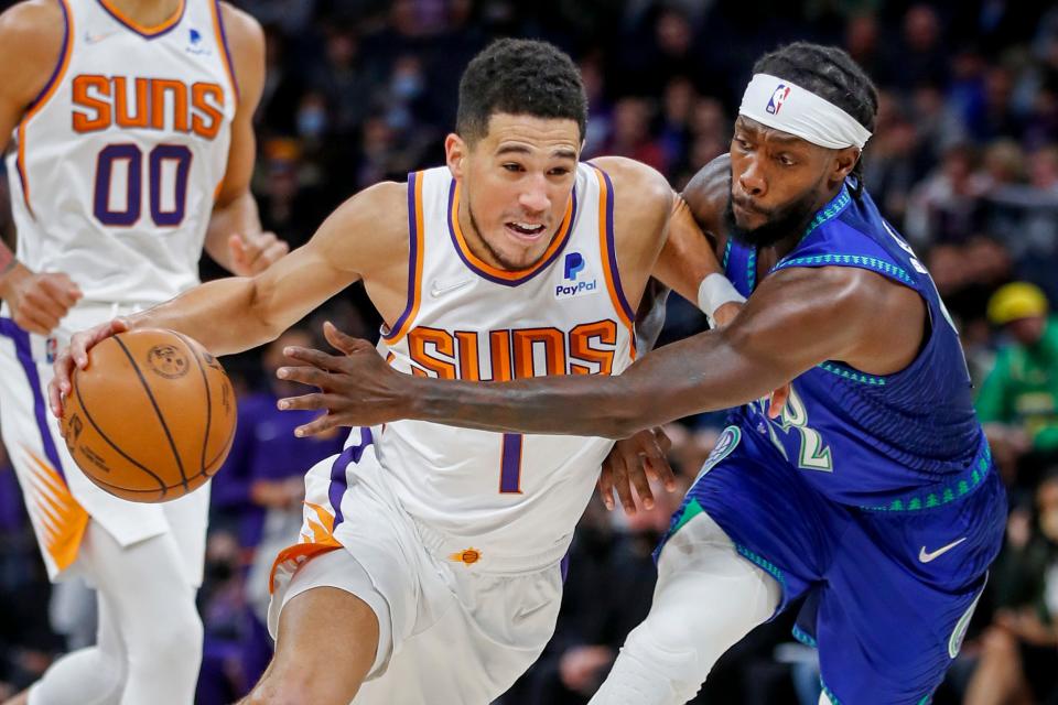 Phoenix Suns guard Devin Booker (1) works around Minnesota Timberwolves guard Patrick Beverley (22) in the first quarter of an NBA basketball game Monday, Nov. 15, 2021, in Minneapolis.