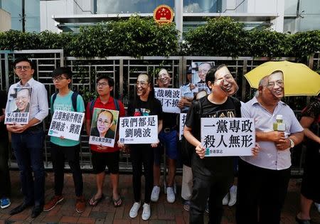Protesters wearing masks of Chinese Nobel rights activist Liu Xiaobo stand outside China's Liaison Office in Hong Kong, China June 27, 2017. REUTERS/Bobby Yip