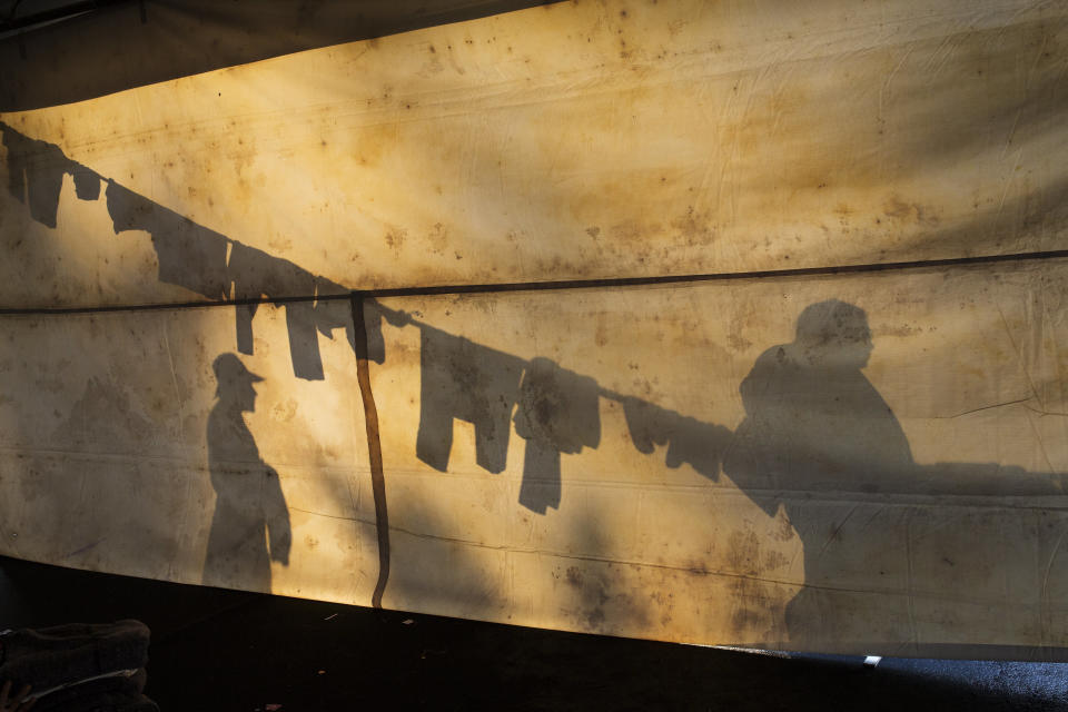 In this Nov. 6, 2018 photo, the silhouettes of Central American migrants are projected on the side of a tent at the Jesus Martinez stadium in Mexico City. Humanitarian aid converged around the stadium in Mexico City where thousands of Central American migrants winding their way toward the United States were resting Tuesday after an arduous trek that has taken them through three countries in three weeks. (AP Photo/Rodrigo Abd)