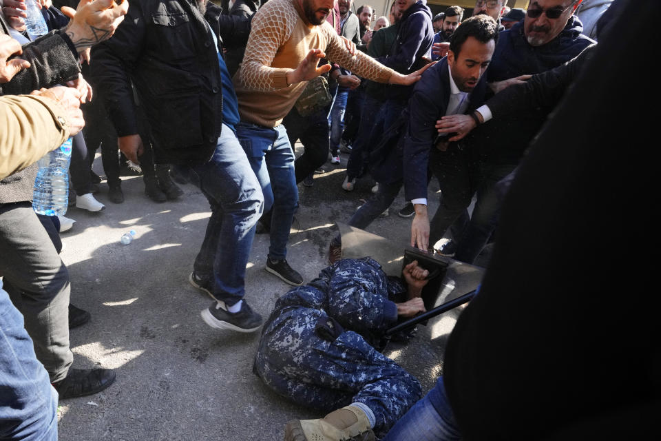 Anti-government protesters beat a riot policeman during scuffle with riot police outside the ministry of Justice, in Beirut, Lebanon, Thursday, Jan. 26, 2023. Scores of protesters Thursday scuffled with riot police as they tried to break into the Beirut Justice Palace, rejecting an order from Lebanon's judiciary that further crippled the probe into a massive port explosion over two years ago. (AP Photo/Hassan Ammar)