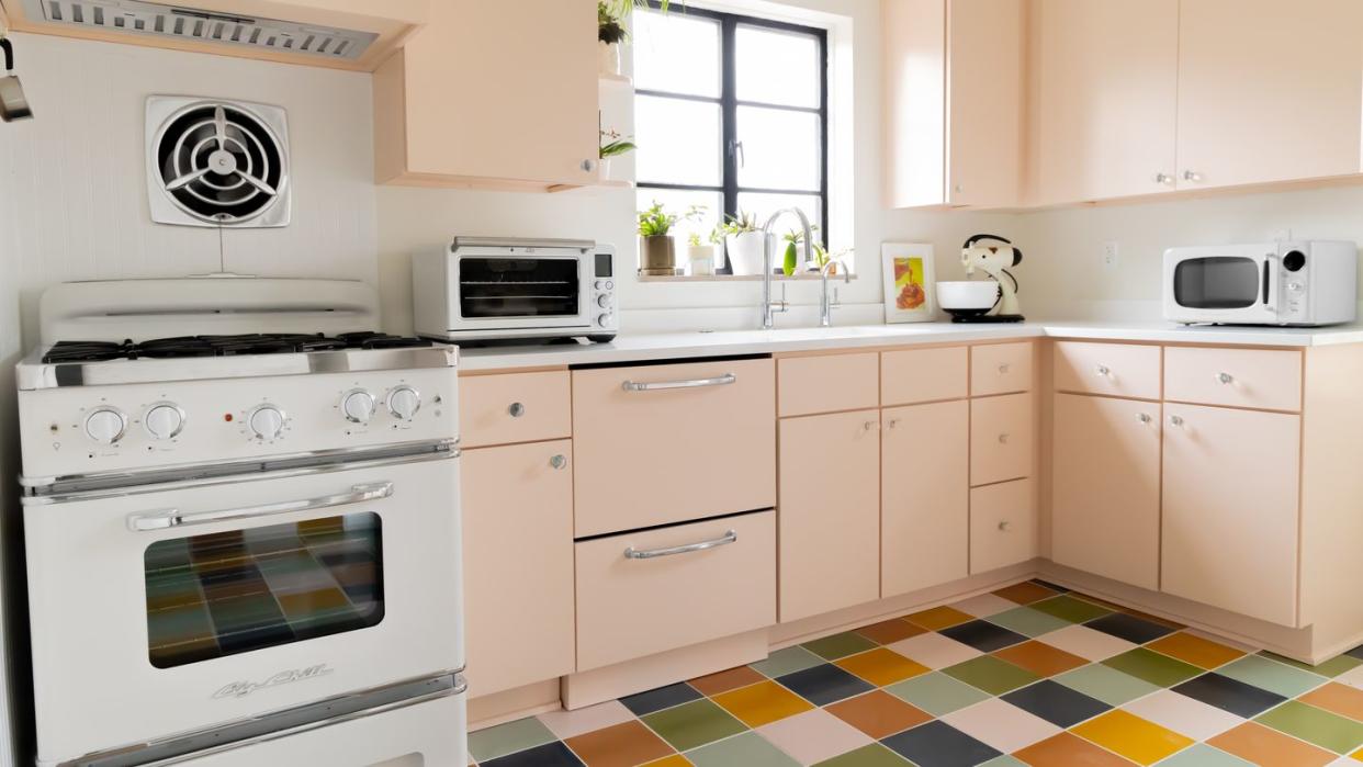 retro style kitchen with blush pink cabinets and checkered floors