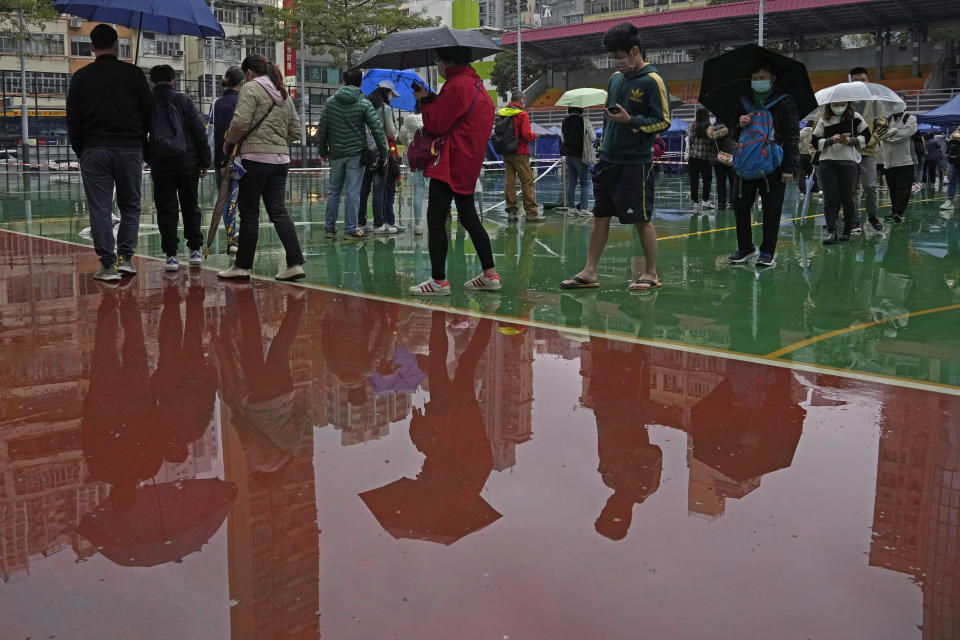Despite the rain, residents line up to get tested for the coronavirus at a temporary testing center in Hong Kong, Thursday, Feb. 17, 2022. Hong Kong on Thursday reported 6,116 new coronavirus infections, as the city’s hospitals reached 90% capacity and quarantine facilities are at their limit, authorities said. (AP Photo/Kin Cheung)