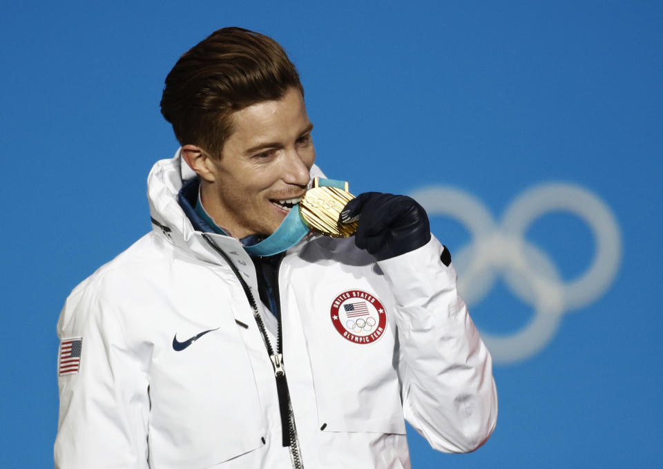 FILE - Men's halfpipe gold medalist Shaun White, of the United States, bites his medal during the medals ceremony at the 2018 Winter Olympics in Pyeongchang, South Korea, Feb. 14, 2018. The Beijing Olympics will be the fifth Olympics for the three-time gold medalist. And the last Olympics for the 35-year-old — get this — elder-statesman who is now more than double the age of some of the riders he goes against. (AP Photo/Patrick Semansky, File)