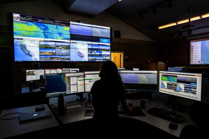 MORENO VALLEY, CA - AUGUST 9, 2023: A Cal Fire worker monitors computer screens which depicts views of wildfire camera systems throughout the state of California at the Southern California Geographic Area Coordination Center on August 9, 2023 in Moreno Valley, CA. The agency is using AI to help monitor the camera systems.(Gina Ferazzi / Los Angeles Times)