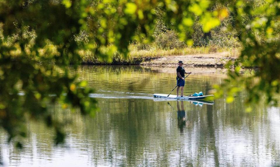 A person uses a stand-up paddle board in Barber Pool, a conservation area next to the Idaho Shakespeare Festival’s land.