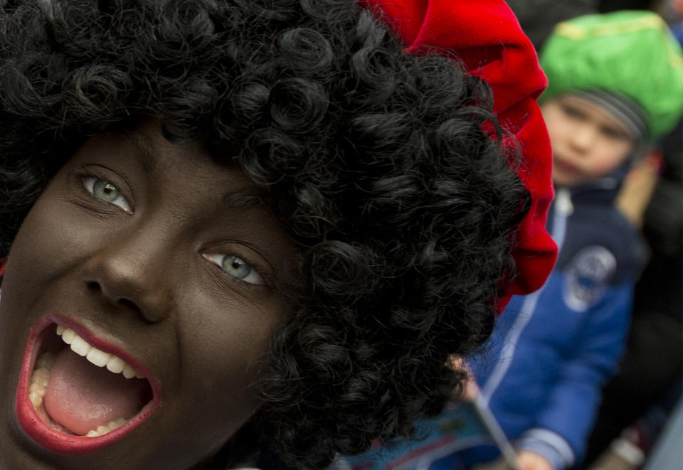 In this Saturday, Nov. 12, 2016 file photo, a Black Pete interacts with children during the arrival of Sinterklaas in Maassluis, Netherlands, Saturday, Nov. 12, 2016. Saturday, Nov. 12, 2016.As many Dutch children eagerly anticipate the arrival of their country's version of Santa Claus this weekend, opponents and supporters of his controversial helper Black Pete are gearing up for protests. Black Pete is often played by white people with their faces daubed in dark makeup. Supporters see him as a traditional children's character, while opponents decry him as a racist stereotype. (AP Photo/Peter Dejong)