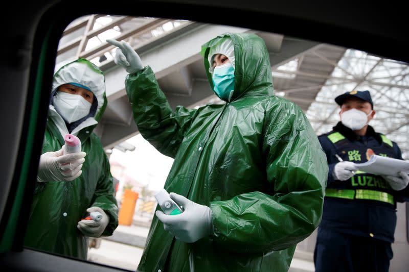 Medical workers and security personell stand at a checkpoint as the country is hit by an outbreak of the novel coronavirus in Susong County