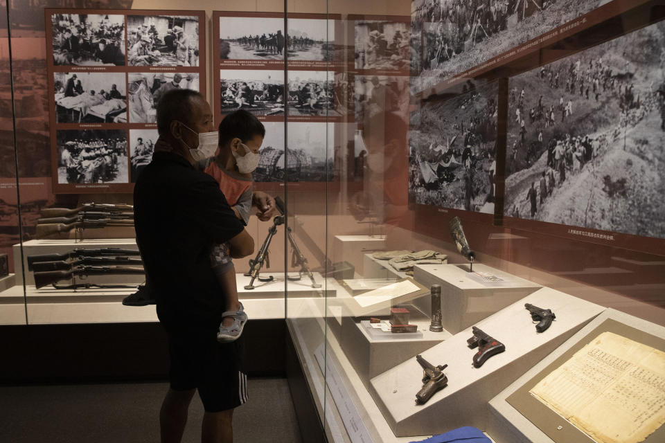 A man and child look at display at an exhibition on the War of Resistance against Japanese Aggression at the military museum in Beijing on Thursday, Sept. 3, 2020. China on Thursday commemorated the 75th anniversary of the end of World War II in the Pacific, during which it endured a brutal invasion and occupation of much of its territory by Japan. (AP Photo/Ng Han Guan)