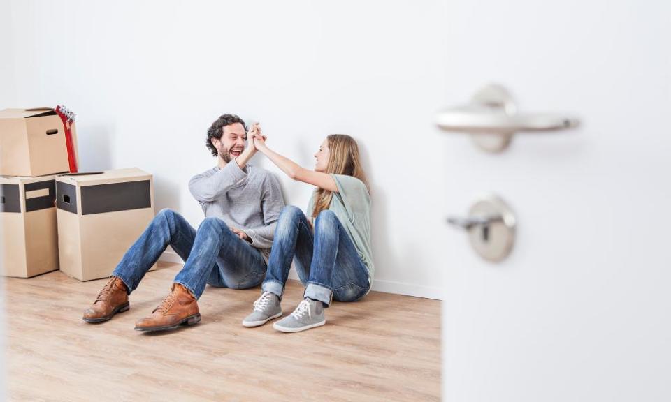 Couple sitting on floor and giving high five, smiling