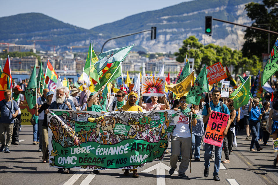 Protestors hold up banners during a demonstration against the World Trade Organization (WTO) in Geneva, Switzerland, Saturday, June 11, 2022. For the first time in 4 1/2 years, after a pandemic pause, government ministers from WTO countries will gather for four days starting Sunday. (Valentin Flauraud/Keystone via AP)
