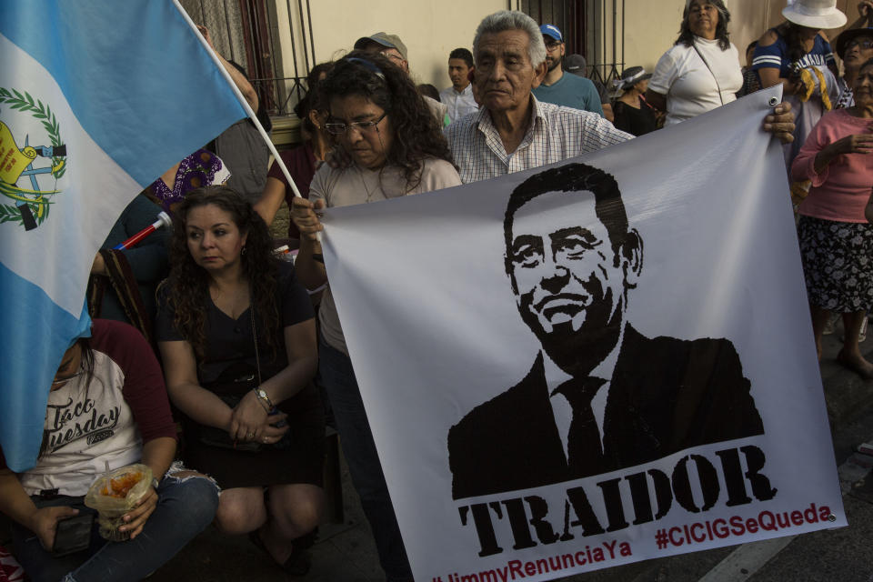 Demonstrators demand the resignation of Guatemalan President Jimmy Morales, featured in the poster that reads in Spanish "Traitor," outside the Presidential House in Guatemala City, Saturday, July 27, 2019. Demonstrators are protesting an agreement that their government signed with Washington to require migrants passing through the Central American country to seek asylum there, rather than pushing on to the U.S. (AP Photo/ Oliver de Ros)