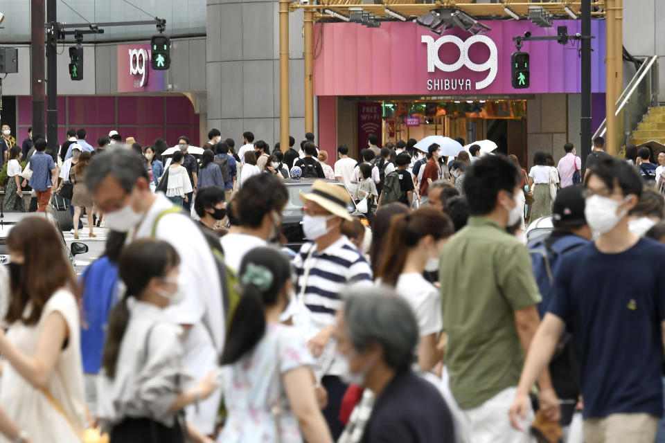 People wearing face masks make their way at an intersection in Tokyo Saturday, Aug. 7, 2021. Tokyo reported more than 4,500 coronavirus cases on Saturday. (Kyodo News via AP)