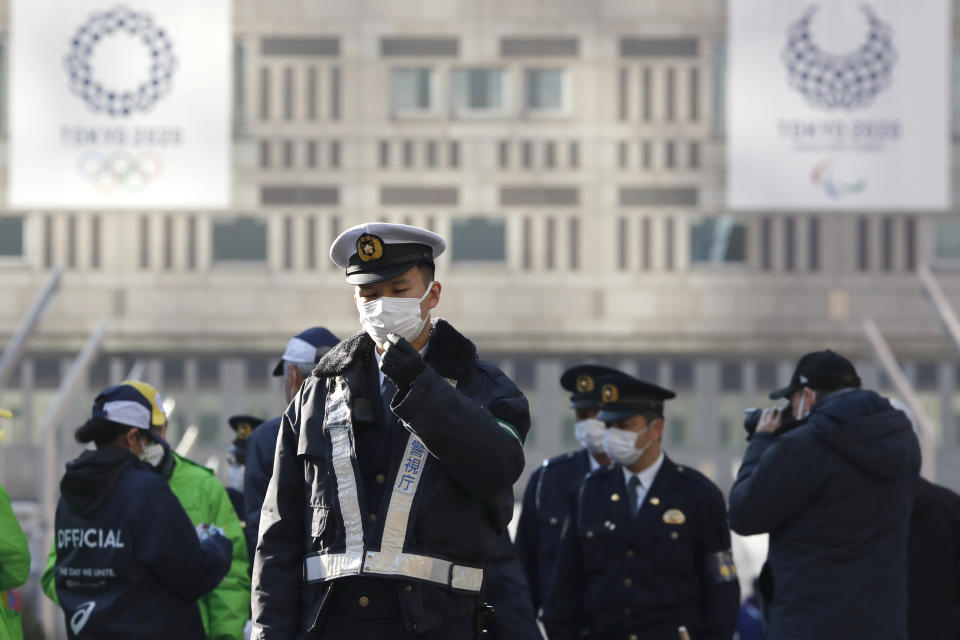 Police officers wearing masks guard before the start of the Tokyo Marathon in Tokyo, Sunday, March 1, 2020. Organizers of the Tokyo Marathon reduced the number of participants out of fear of the spread of the coronavirus from China. The general public was essentially barred from the race. (AP Photo/Shuji Kajiyama)