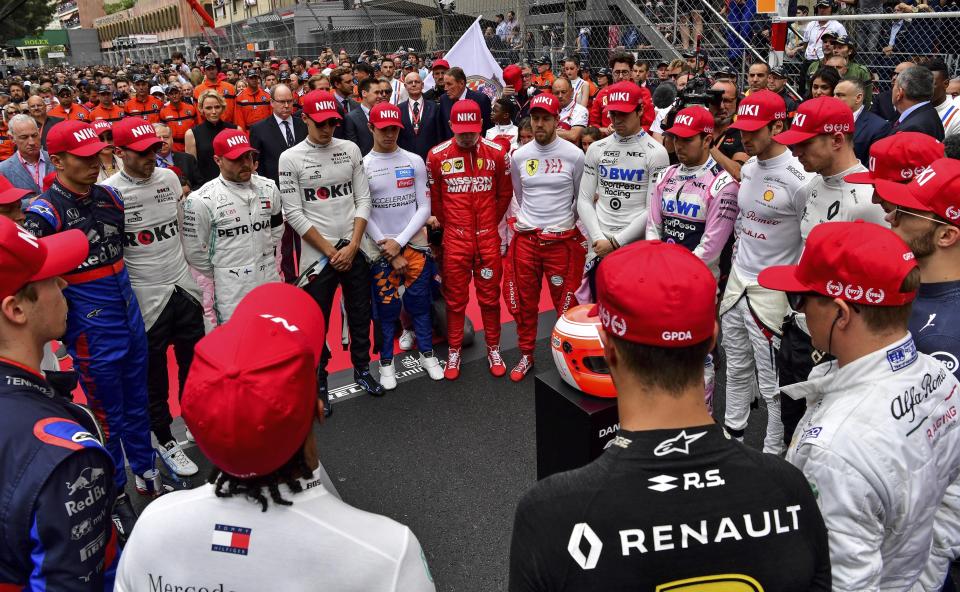 The drivers clap hands around a red helmet on a podest, reading 'Thank you Niki', during a minute of silence to tribute F1 legend Niki Lauda prior the Monaco Formula One Grand Prix race, at the Monaco racetrack, in Monaco, Sunday, May 26, 2019. The former F1 champion Niki Lauda died last week. (Andrej Isakovic/Pool Photo via AP)