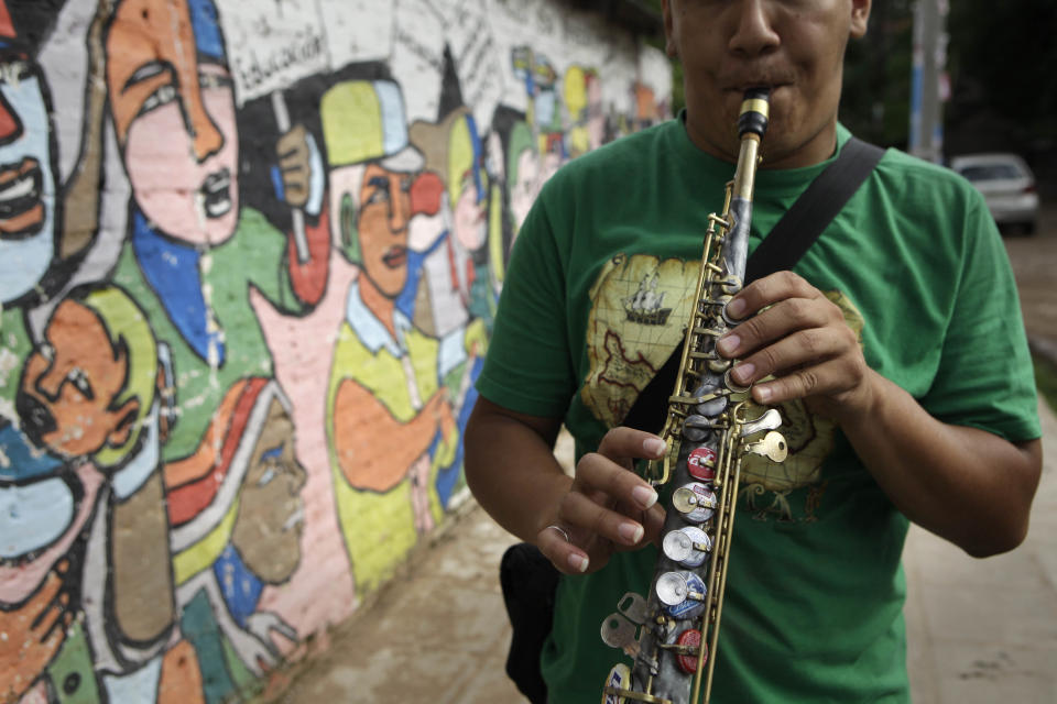 In this Dec. 11, 2012 photo, Oscar Molina plays a saxophone that was repaired with recycled materials outside the school where he practices with “The Orchestra of Instruments Recycled From Cateura” in Cateura, a vast landfill outside Paraguay's capital of Asuncion, Paraguay. The community of Cateura could not be more marginalized. But the music coming from garbage has some families believing in a different future for their children. (AP Photo/Jorge Saenz)