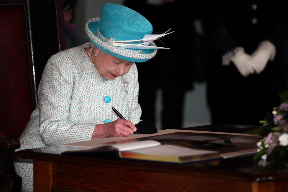 NORFOLK, ENGLAND - FEBRUARY 6: Queen Elizabeth II sign's a photograph of herself and The Duke of Edinburgh during a visit to Kings Lynn Town Hall on February 6, 2012 in Norfolk, England. Today is Accession Day, with the Queen celebrating 60 years to the day since she became Monarch. (Photo by Chris Radburn - WPA Pool/Getty Images)