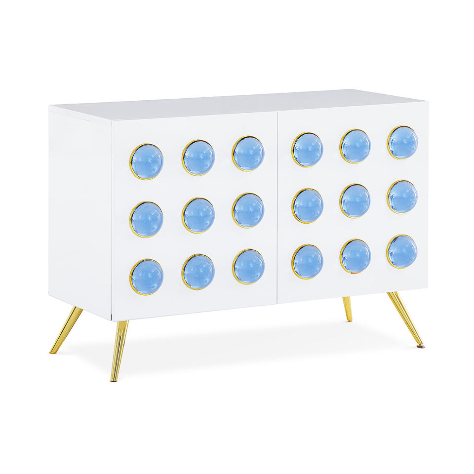 Jonathan Adler’s spring collection includes the Globo cabinet, which nods to trending Art Deco. The cabinet is faced with rows of blue acrylic cabochons set in brass, on a white lacquer base. (Jonathan Adler via AP)