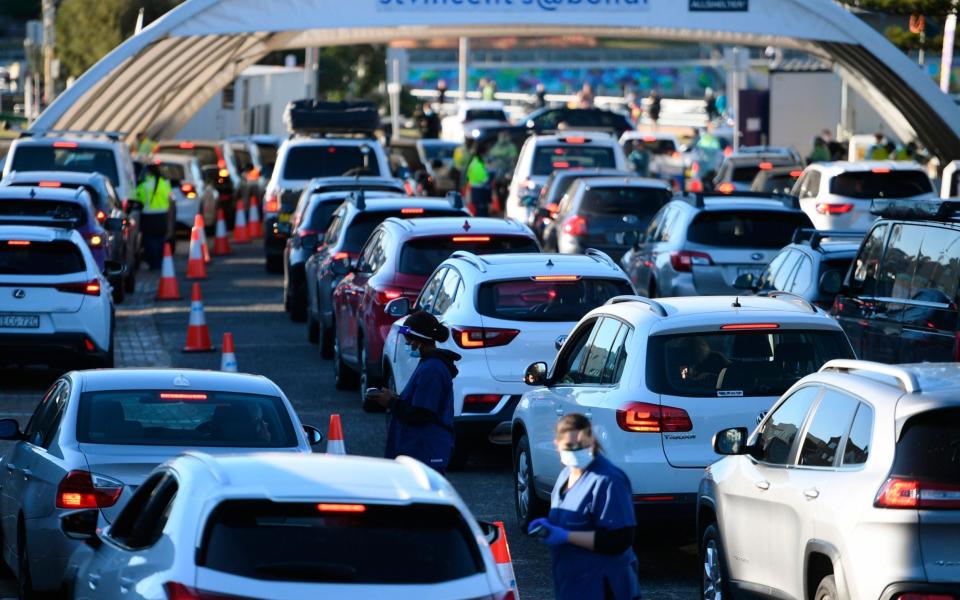 People queue in their cars to get tested at a pop-up testing clinic at Bondi Beach in Sydney - AAP