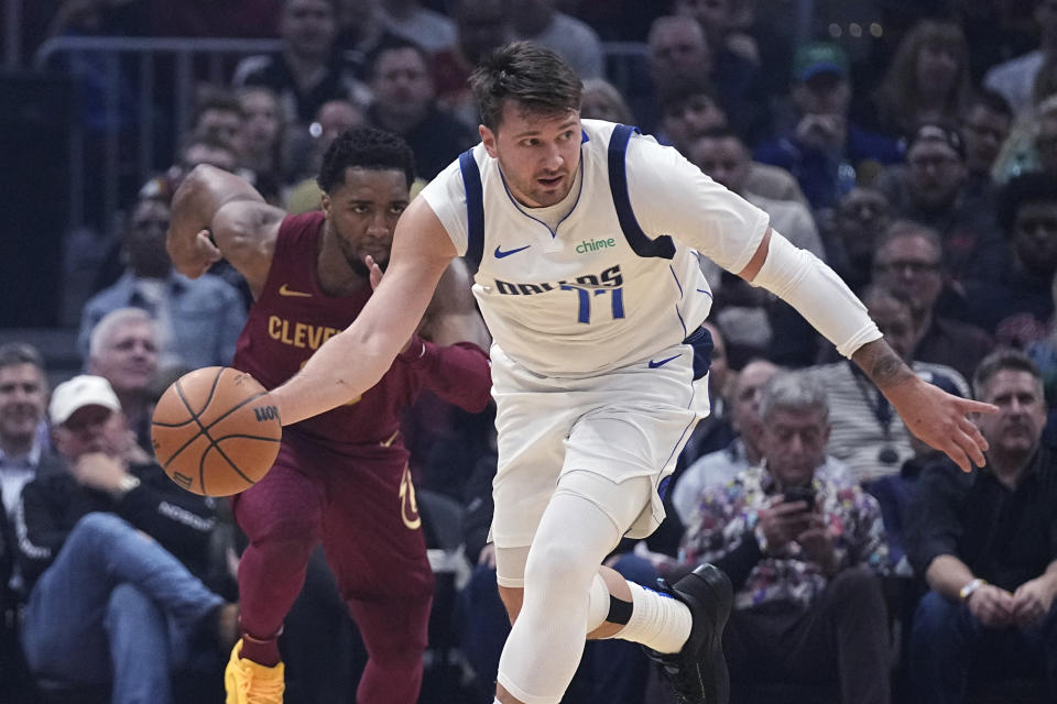 Dallas Mavericks guard Luka Doncic (77) brings the ball up in front of Cleveland Cavaliers guard Donovan Mitchell during the first half of an NBA basketball game Tuesday, Feb. 27, 2024, in Cleveland. (AP Photo/Sue Ogrocki)