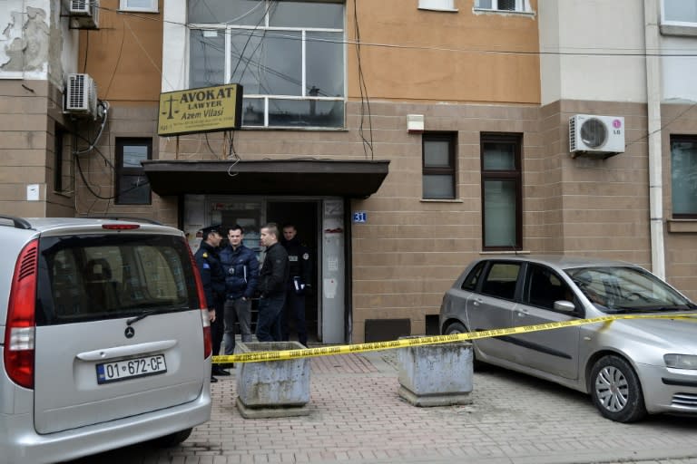 Kosovo's police officers stand at the bottom of the building where prominent lawyer, Azem Vllasi was wounded in an armed attack on March 13, 2017 in Pristina