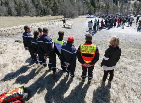 Rescuers stand ready as relatives pay their respects at the memorial for the victims of the air disaster in the village of Le Vernet, near the crash site of the Airbus A320 in French Alps March 27, 2015. REUTERS/Robert Pratta