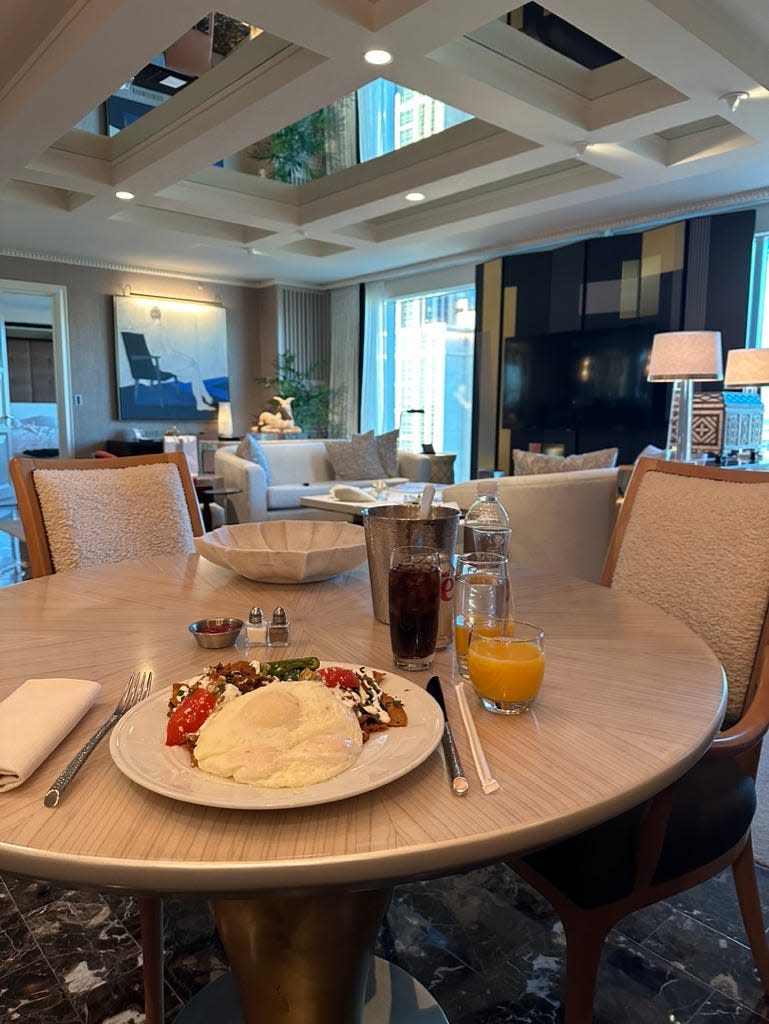 A plate with an egg and food on a circular table in a nice looking hotel room.